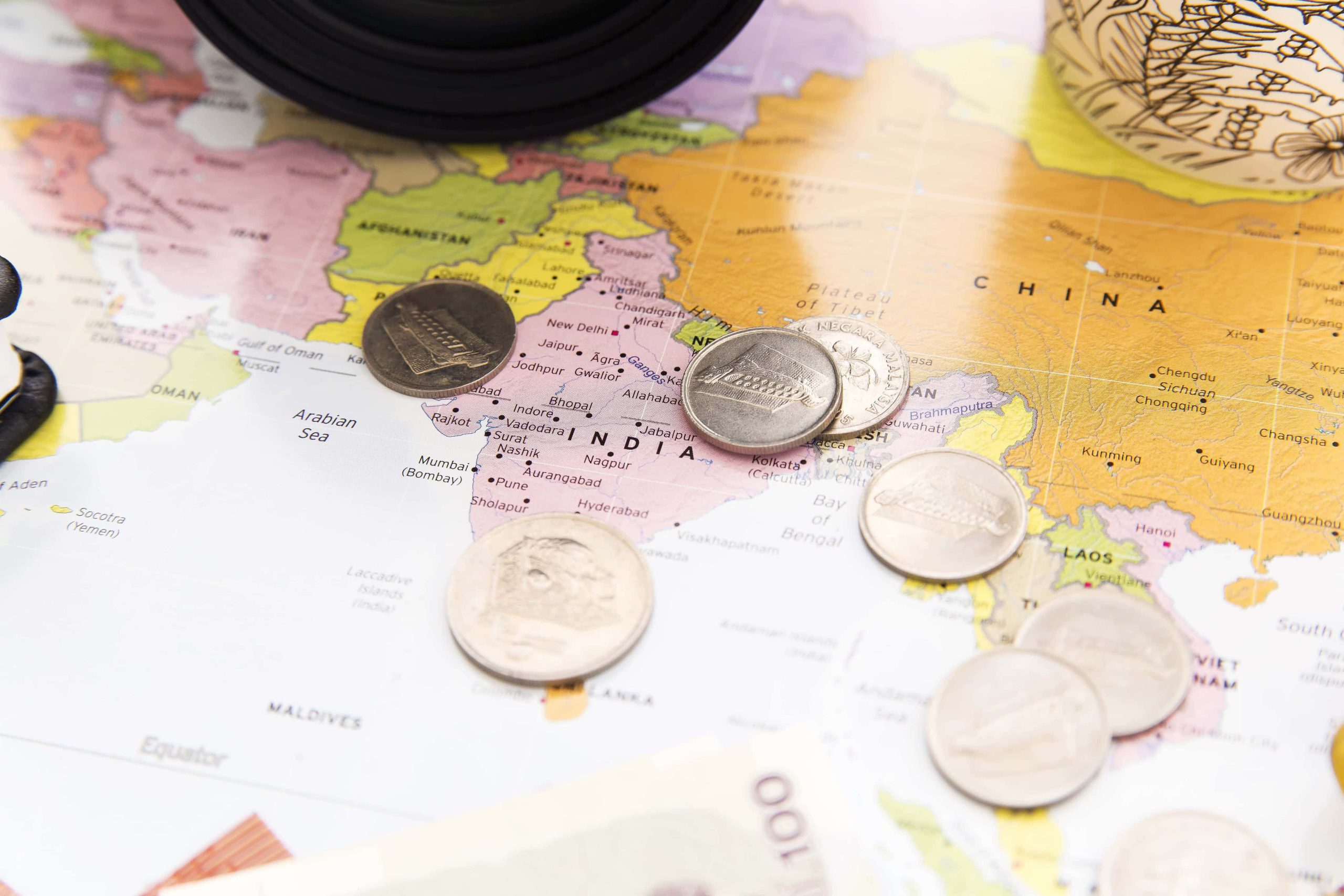 Carte du monde avec des pièces par dessus - concilier vacances et budget