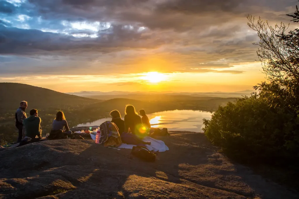 Voyageurs admirant un coucher de soleil sur une colline